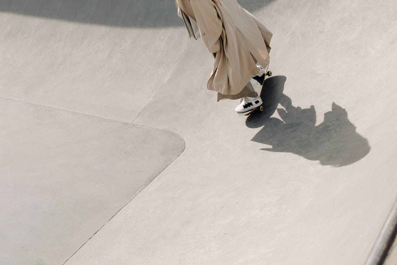 Skateboarder in trench coat rides at a skate park showcasing modern urban style.